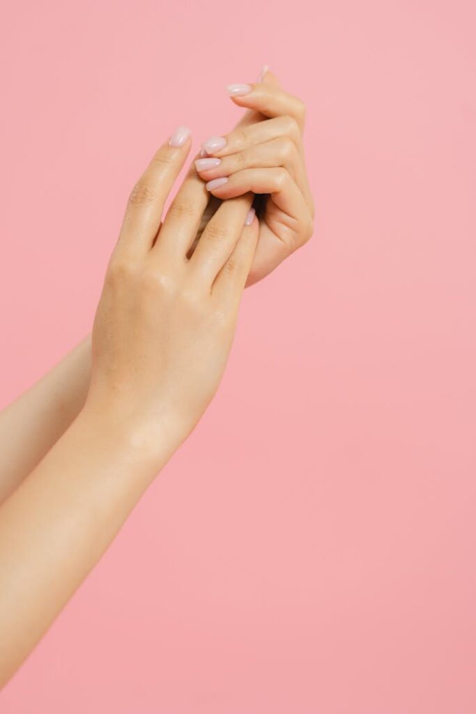 Crafting Captivating Headlines: Your awesome post title goes here Close-up of elegant manicured hands with a pink background, showcasing nail care and beauty.